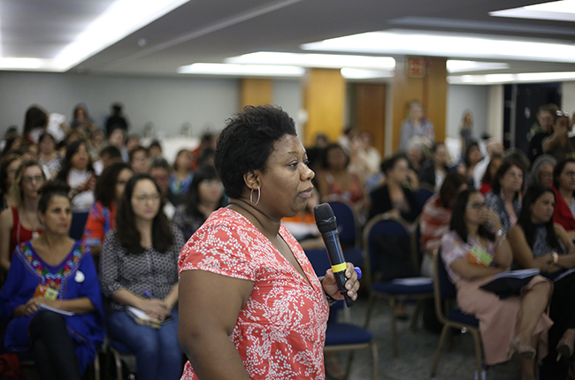 Foto mostra conselheira Solange Moreira em pé, apresentando dados para os/as participantes