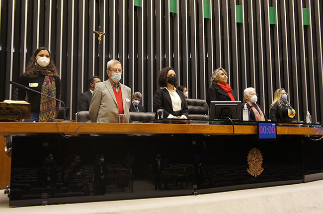 Imagem mostra os integrantes da mesa no Plenário da Câmara dos Deputados, em pé. 