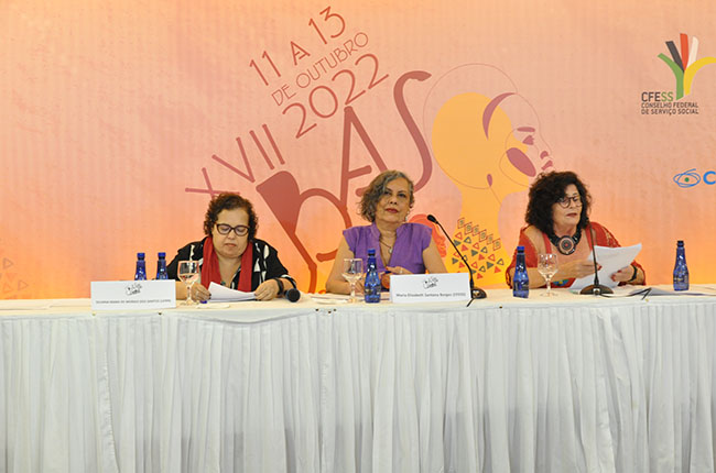 Mesa traz a conferência com as professoras Silvana Mara à esquerda, a presidente do CFESS, Elizabeth Borges ao centro, e a professora Elisabete Mota à direita. 