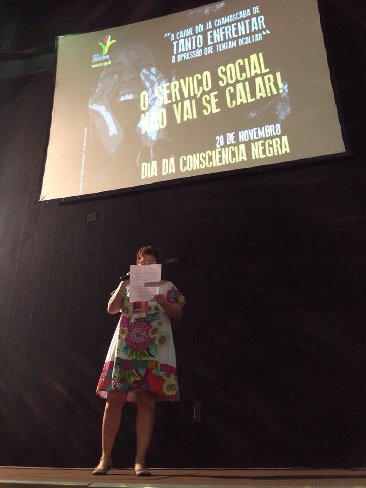 Imagem da conselheira do CFESS Daniela Castilho declamando um poema sobre a consciência negra, durante o evento