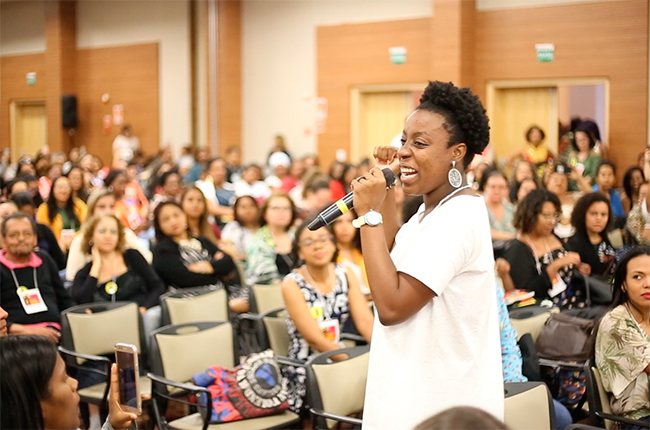Imagem mostra artista negra fazendo sua apresentação diante do público do evento