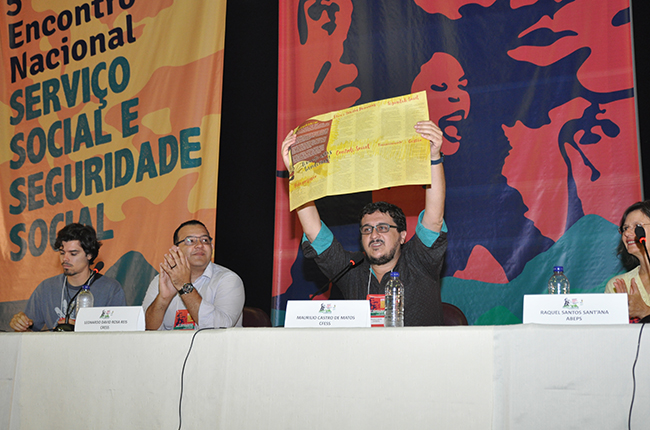 Imagem do presidente do CFESS, lançando o folder com as bandeiras de luta do Serviço Social