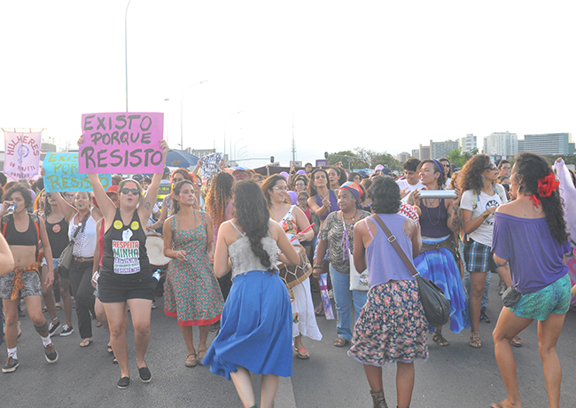 Foto mostra mulheres marchando e segurando placas com palavras de ordem