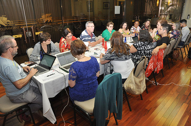 Imagem mostra a comissão organizadora da Conferência, reunida em volta de uma mesa.