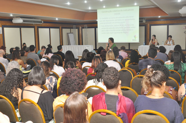 Imagem mostra participantes reunidos no eixo da Formação Profissional, durante a fala da conselheira do CFESS Daniela Neves à frente.