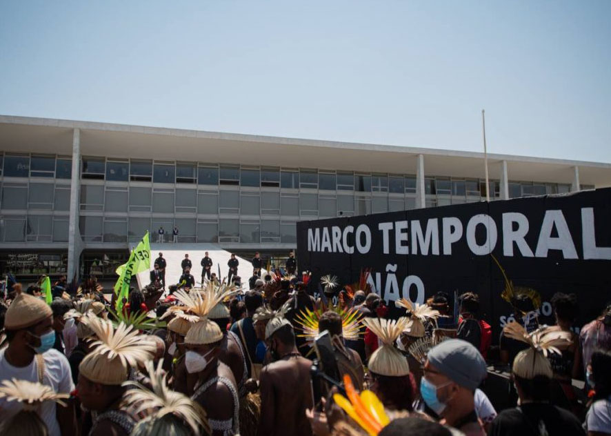 Imagem mostra povos indígenas mobilizados em frente ao Palácio do Planalto, em Brasília, com uma faixa com a mensagem: Marco Temporal Não.