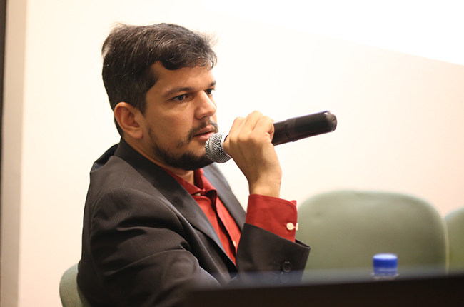 Foto do palestrante Diego segurando o microfone na mesa de debate