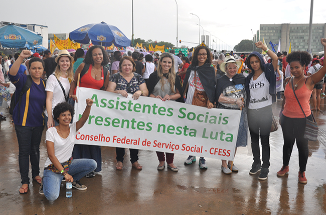 Foto mostra estudantes e profissionais com a faixa 'assistentes sociais na luta'