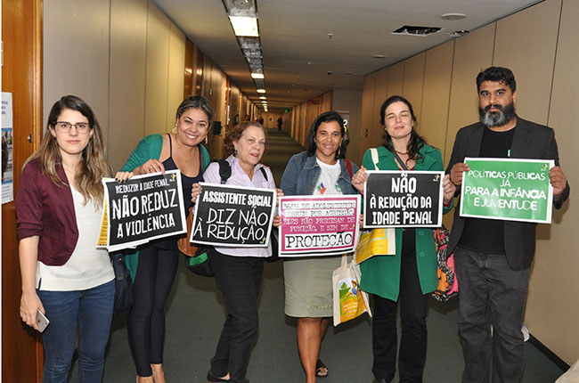 Imagem mostra integrantes da Frente contra a Redução da Maioridade Penal segurando cartazes nos corredores da  Câmara