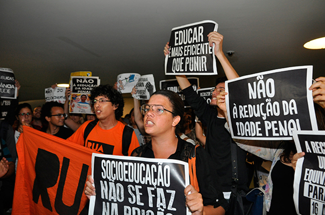 Foto mostra manifestantes nos corredores do Congresso Nacional segurando cartazes com dizeres contrários à redução da maioridade penal